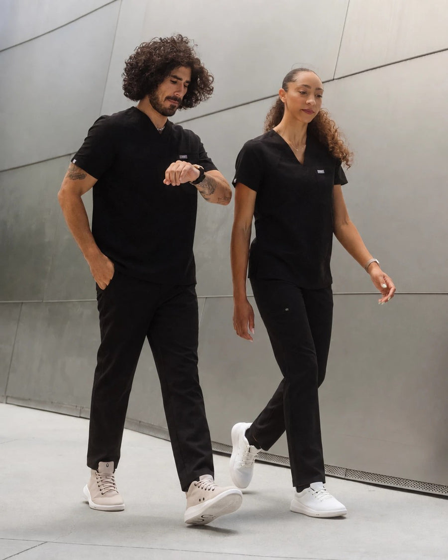 Two healthcare workers in black scrubs walking in Perform Sand Mid and Perform Whiteout Low