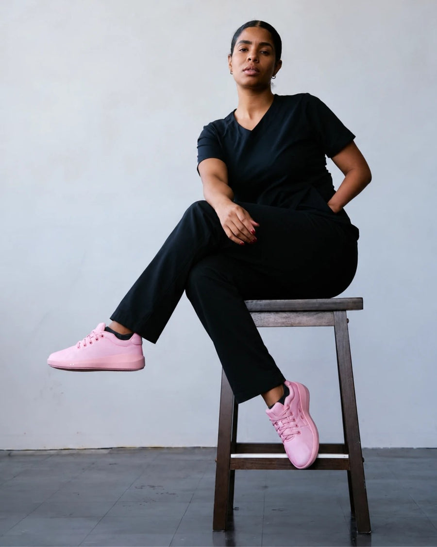 Healthcare worker in black scrubs sitting on a stool in Perform Paloma