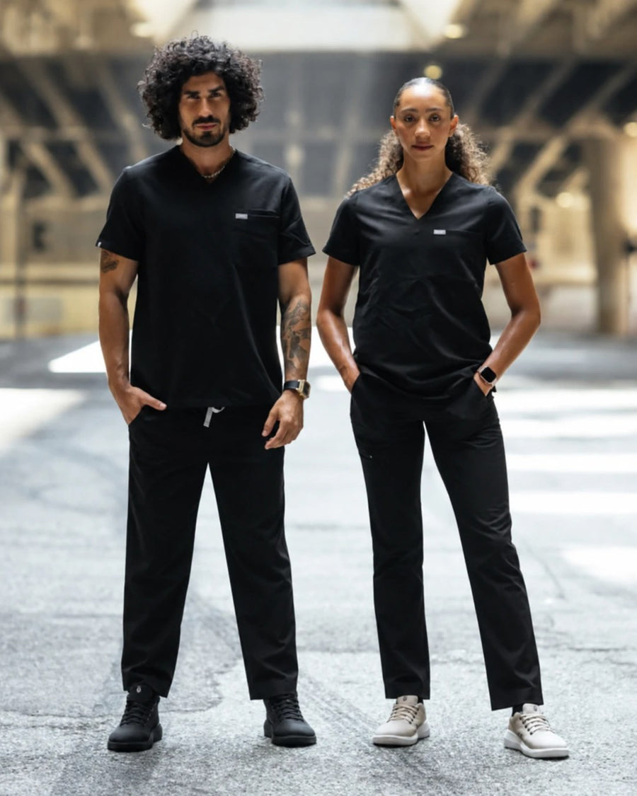 Two healthcare workers in black scrubs wearing Perform Blackout Mid and Perform Sand Low